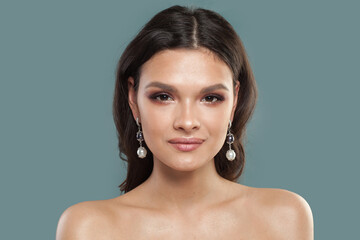 Beautiful female face. Brunette woman in jewelry pearl earring, fashion beauty portrait