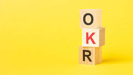 wooden blocks with the text OKR on a bright yellow background