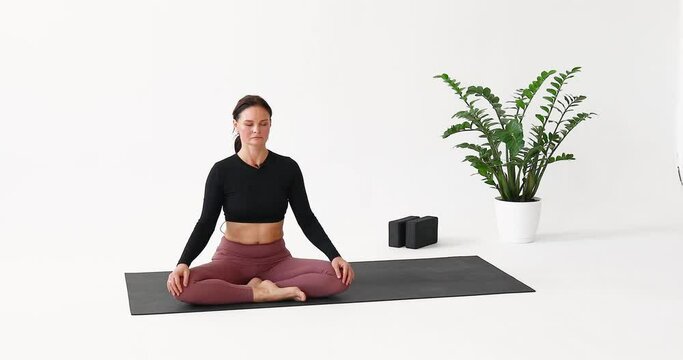A woman performs the Kapalabhati exercise for the respiratory tract, cleanses the lungs and paranasal sinuses, inhales and exhales through the nose, and trains while sitting in the lotus position