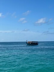Vertical shot of a boat on bright blue water under a clear sky
