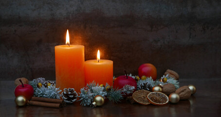 Romantic Christmas decoration with burning candles, fir branches, cinnamon sticks and orange slices with space for text.
