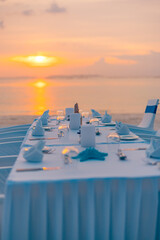 Obraz premium Concept of a tropical destination wedding in front of the ocean. Beautiful wedding arch on the beach. Table setting at a luxury wedding and Beautiful flowers on the table. Dream sunset decoration