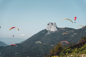 Aerial shot of a group of people paragliding in the sky above a majestic mountain peak