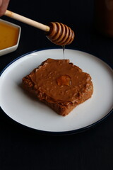Peanut butter sandwich with honey on a black background