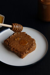 Peanut butter sandwich with honey on a black background