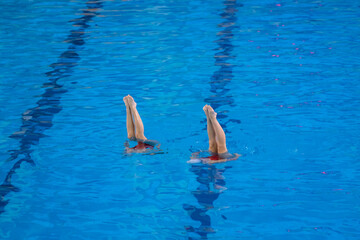 artistic performance in swimming pool, group of women doing synchrone moves in the water, legs...