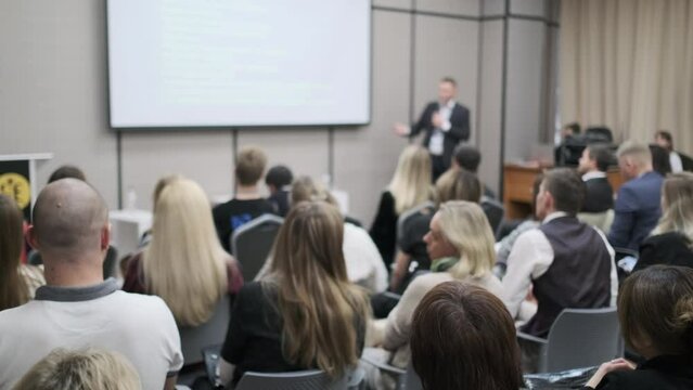 Back view of business executives listening to male professional explaining strategy during conference at export forum