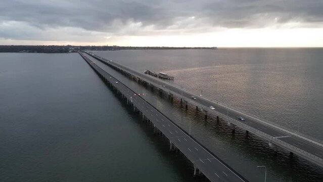 Aerial timelapse of the traffic on the bridge over the water under the gloomy sky