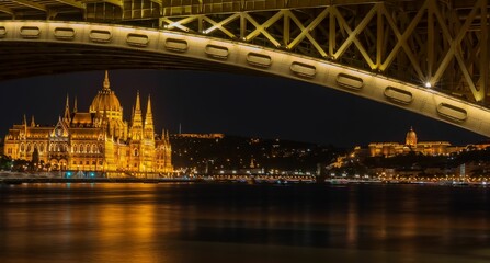 a large bridge over the water and buildings are lit up in yellow lights
