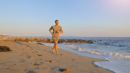 Athletic man jogging at the beach in Southern California. Slow Motion.