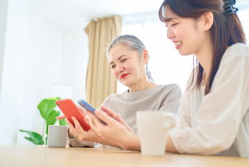 スマートフォンを操作するシニア女性と若い女性