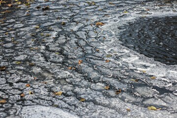 Closeup shot of a tranquil pond with broken ice, illuminated by the sunlight