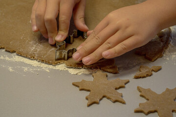 Children's hands cut out cookies from dough with a cookie cutter