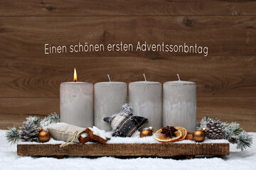 Erster Advent: Adventsdekoration mit einer brennenden Kerze vor einem braunen Holzhintergrund. Mit...