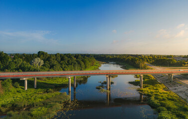 Fototapeta na wymiar Bridge over the river in morning sunlight from aerial view. Red color bridge