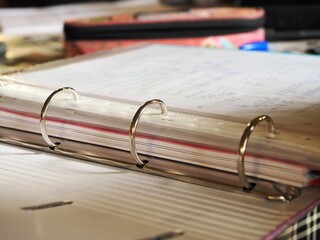 Open ring binder with handwritten papers on a desk
