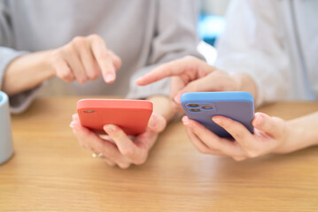 スマートフォンを操作する女性たちの手元