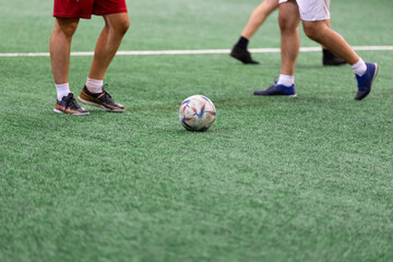 Five-a-side soccer players playing game in indoor stadium on artificial turf.