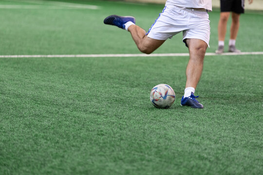 Football Futsal ball and man player legs on artificial grass field indoors.