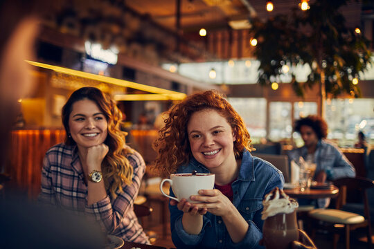 Young woman holding a mug in cafe with friends