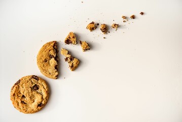 Chocolate chip cookie with broken pieces of the cookie, crumbled and scattered around it