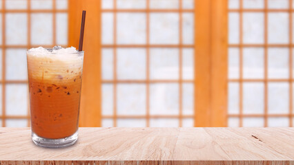 Iced thai milk tea in glass, Milk ice tea, Cheddar is a traditional Thai drink on wooden table,...