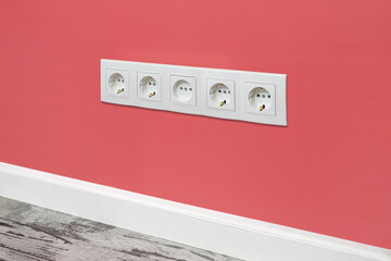White five-way wall power socket on the pink wall