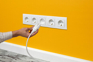 Man plugging cord into a electrical outlet.