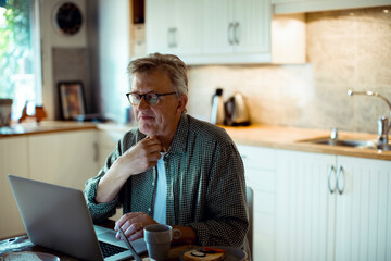 Mature man holding throat working on laptop at home
