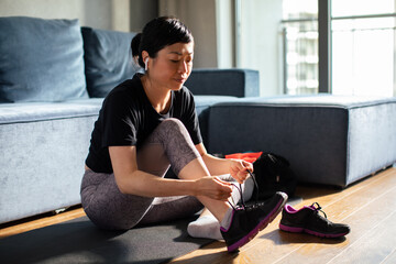 Mature fitness woman tie shoelaces at home