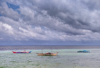 Fleet of small boats in a calm sea in front of a cloudy sky