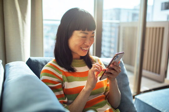 Young Japanese woman using smartphone on sofa