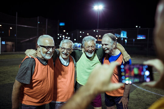 Senior men posing for picture on soccer field at night
