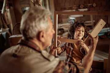 Little boy learning in grandfather carpenter shop