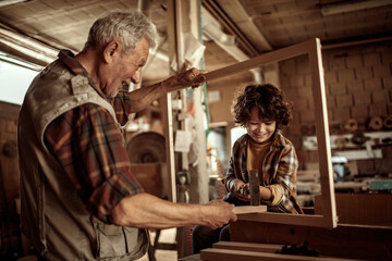 Little boy learning in grandfather carpenter shop