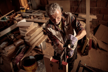Skilled carpenter cutting a piece of wood in his workshop