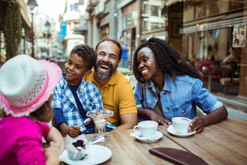 Happy multiethnic family sitting in outdoor cafe