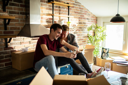 Gay couple looking at phone in new home