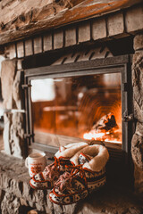 Christmas comfortable slippers by the warm cozy fireplace. Relaxing atmosphere in a chalet by authentic vintage fireside with a cup of hot drink. Winter and Christmas holidays concept.