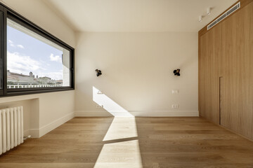 Beautiful contemporary design room with a custom wardrobe with oak doors, a large window with views and wooden floors in light tones
