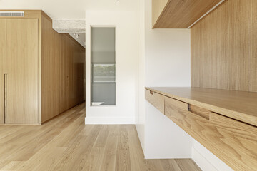 Contemporary designed bedroom with custom oak door closet, skylight leading to ensuite bathroom, raw concrete beams, wall-mounted desk