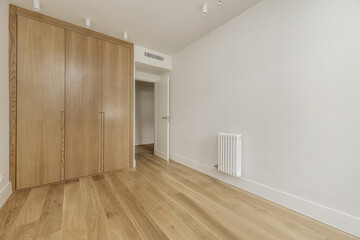 Empty bedroom with custom built built-in wardrobe with light oak wooden doors, ducted air...