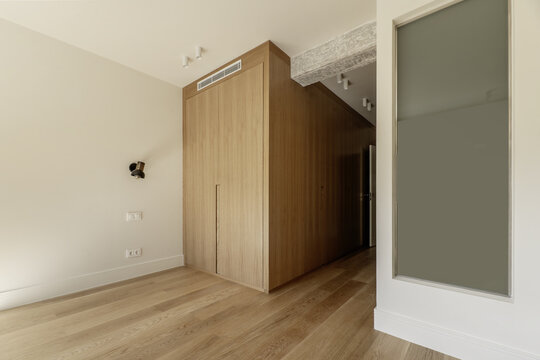 Beautiful contemporary designed room with custom wardrobe with oak doors, skylight to the en-suite bathroom, raw concrete beams and light colored wooden floors
