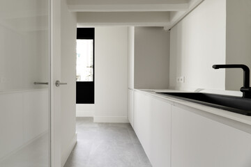 aundry room of a home with smooth white wooden furniture with a black synthetic sink with a faucet of the same color