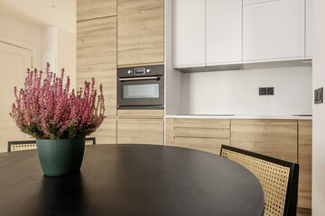 Modern open kitchen with wall clad with handleless wooden furniture, integrated black glass...
