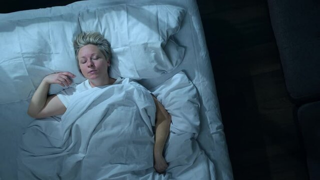 Sleeping man talking in his sleep in bed, top view. Woman suffering from parasomnia sleep disorders.