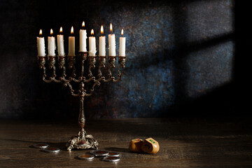 Jewish religious holiday Hanukkah with holiday Hanukkah (traditional candelabra) and dreidel on a dark background