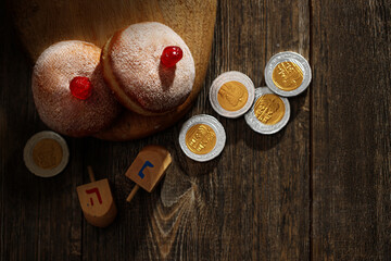 Hanukkah donutsand traditional spinning dreidel on a wooden board.  Close up