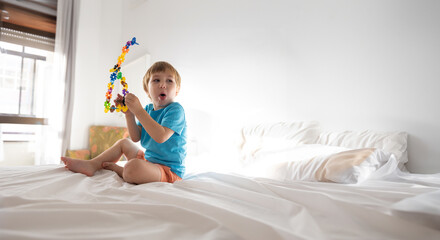 Little white hair boy 3 years old plays with his toys - space for text
