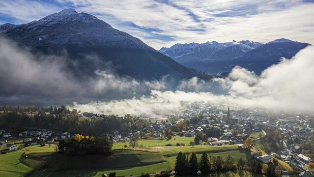 drone time lapse video moving away from the city "Imst" in the Tyrolean Alps with morning fog